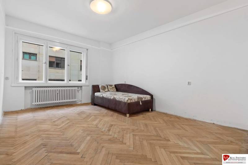 Predaj 4-izbový byt, 102m2, terasa 50m2, Bratislava-centrum, Gorkého - Miestnosť v 4-izbovom byte s podlahou s dreveným dekorom a rozkladacou sedačkou.