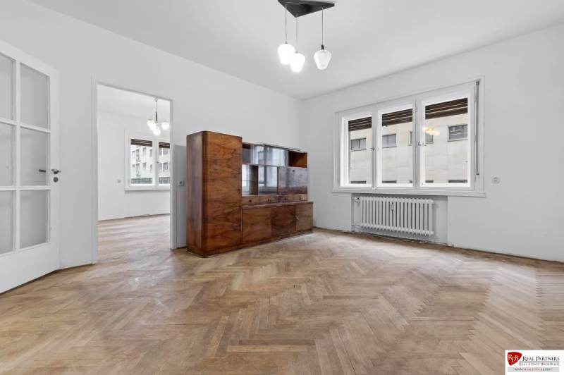 Predaj 4-izbový byt, 102m2, terasa 50m2, Bratislava-centrum, Gorkého - Obývacia izba s vitrínou, podlahou s dreveným dekorom a bielymi stenami v 4-izbovom byte.