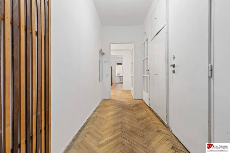 Predaj 4-izbový byt, 102m2, terasa 50m2, Bratislava-centrum, Gorkého - Chodba s bielymi stenami, podlahou s dreveným dekorom a drevenými lištami v 4-izbovom byte.