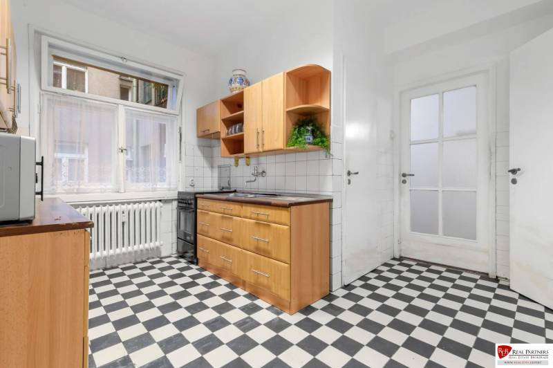 Predaj 4-izbový byt, 102m2, terasa 50m2, Bratislava-centrum, Gorkého - Kuchyňa v 4-izbovom byte s čiernobielou dlažbou a dreveným dekorom kuchynskej linky.