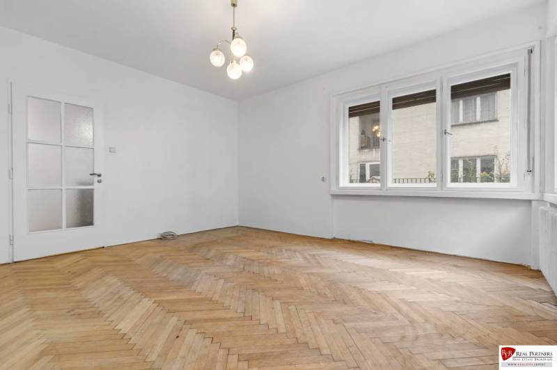 Predaj 4-izbový byt, 102m2, terasa 50m2, Bratislava-centrum, Gorkého - Obývačka v 4-izbovom byte s podlahou s dreveným dekorom a veľkými oknami.