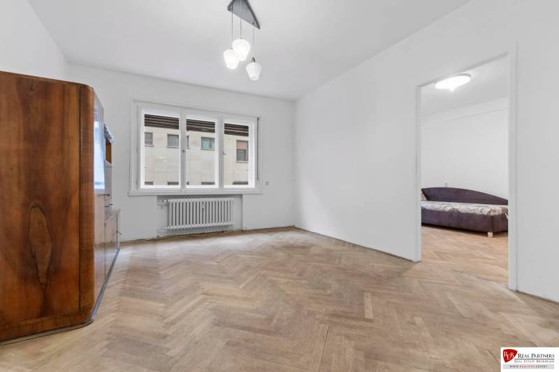 Predaj 4-izbový byt, 102m2, terasa 50m2, Bratislava-centrum, Gorkého - Obývacia izba v 4-izbovom byte s podlahou s dreveným dekorom a veľkým oknom.