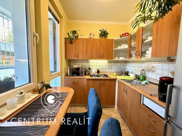 1 izb. zrekonštruovaný byt s veľkou loggiou, Karlova Ves - Kuchyňa v 1-izbovom byte s drevenými skrinkami a jedálenským stolom.