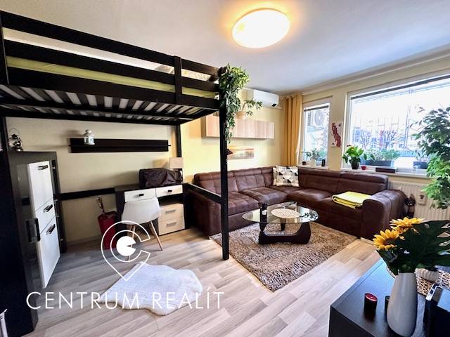 1 izb. zrekonštruovaný byt s veľkou loggiou, Karlova Ves - Obývacia izba s poschodovou posteľou, sedačkou a podlahou s dreveným dekorom v 1-izbovom byte.