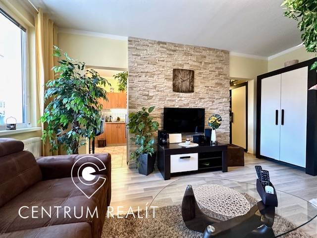 1 izb. zrekonštruovaný byt s veľkou loggiou, Karlova Ves - Obývacia izba v 1-izbovom byte s rastlinami a podlahou s dreveným dekorom.