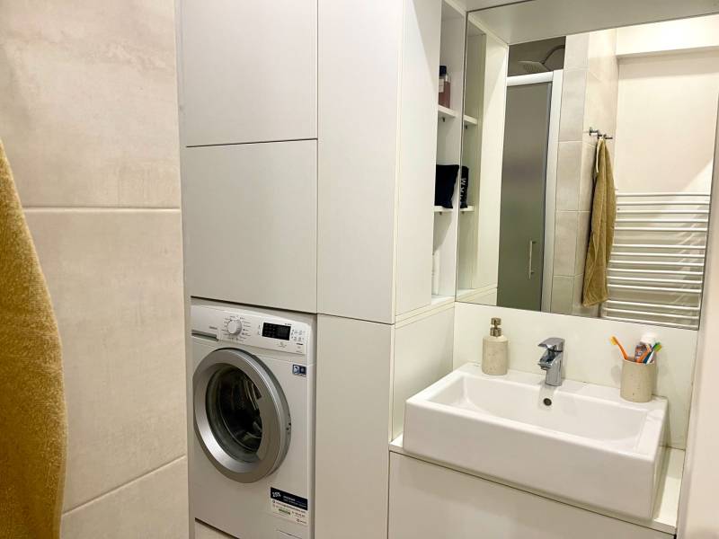 | Predaj 1-izbového bytu – Račianska, Bratislava - Kúpeľňa v 1-izbovom byte so sprchou, umývadlom a práčkou.