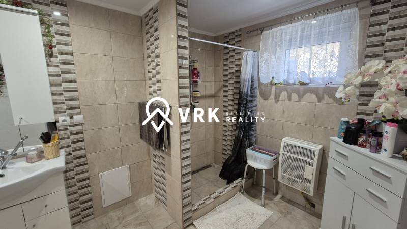 3 IZBOVÝ RODINNÝ DOM S GARÁŽOU, VEĽKÉ OZOROVCE - Kúpeľňa v rodinnom dome s obkladom a sprchovým kútom, dekorovaná kvetmi.