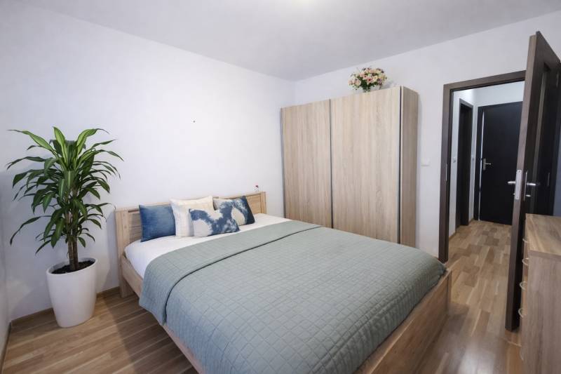 REZERVOVANÉ Prenájom  2-izbového bytu v Petržalke - Spálňa v 2-izbovom byte s posteľou, skriňou a podlahou s dreveným dekorom.