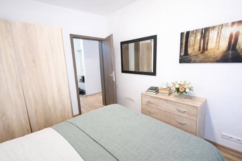 REZERVOVANÉ Prenájom  2-izbového bytu v Petržalke - Spálňa v 2-izbovom byte so skriňou, komodou a podlahou s dreveným dekorom.