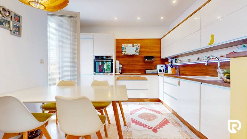 4i byt s atmosférou domu, terasou a parkovaním | Vrakuňa, 129m2 - Kuchyňa v 4-izbovom byte, podlaha s dreveným dekorom, jedálenský stôl, biele skrinky.