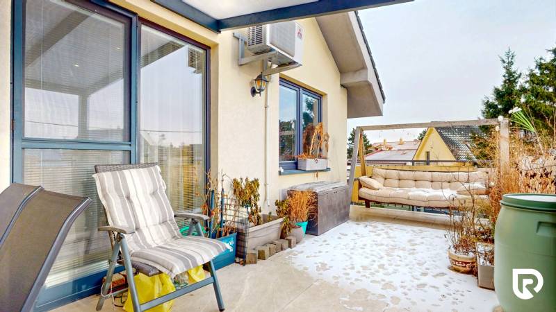 4i byt s atmosférou domu, terasou a parkovaním | Vrakuňa, 129m2 - Zasnežená terasa 4-izbového bytu s kreslom, rastlinami a pohovkou.