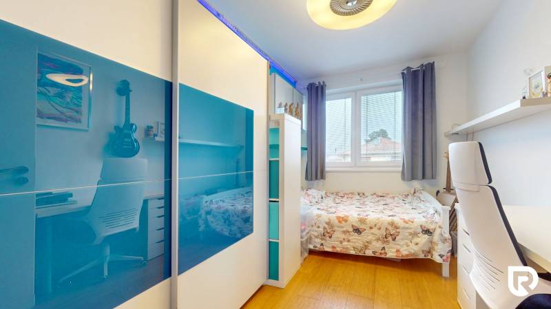 4i byt s atmosférou domu, terasou a parkovaním | Vrakuňa, 129m2 - Izba v 4-izbovom byte s posteľou, písacím stolom a podlahou s dreveným dekorom.