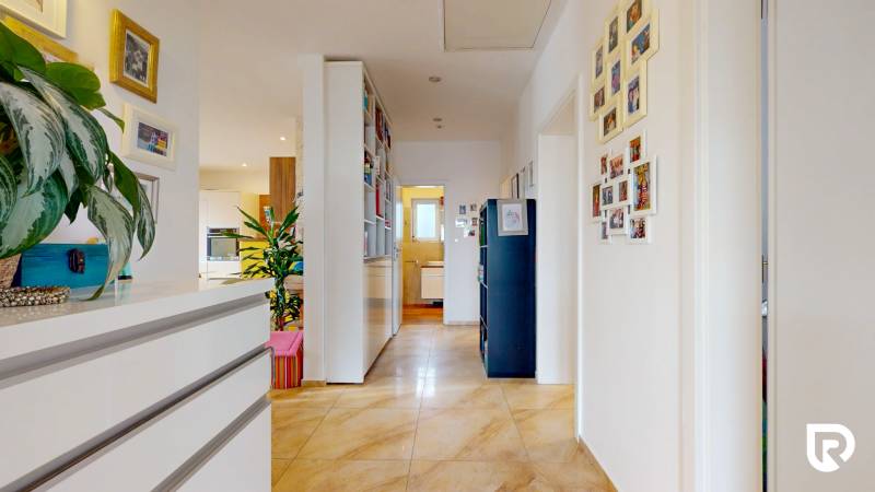 4i byt s atmosférou domu, terasou a parkovaním | Vrakuňa, 129m2 - Chodba v 4-izbovom byte s dekoráciami, rastlinami a dlažbou na podlahe.