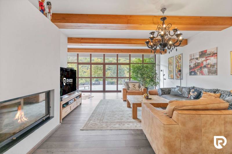 Nadštandardná 6-izbová vila v prominentnej lokalite - Interiér vily s krbom, drevenými trámami a veľkými oknami, útulné sedacie kúty.