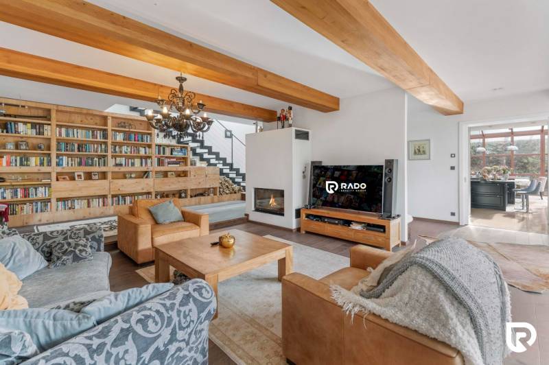 Nadštandardná 6-izbová vila v prominentnej lokalite - Obývacia izba vily s knižnicou, sedacou súpravou a krbom, prepojená s jedálňou.