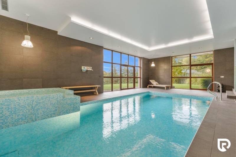 Nadštandardná 6-izbová vila v prominentnej lokalite - Vnútorný bazén vo vile s veľkými oknami, drevenými lavicami a zeleným výhľadom.