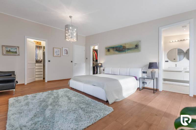 Nadštandardná 6-izbová vila v prominentnej lokalite - Spálňa vo vile s bielou posteľou, šatníkom a kúpeľňou s kruhovým zrkadlom.