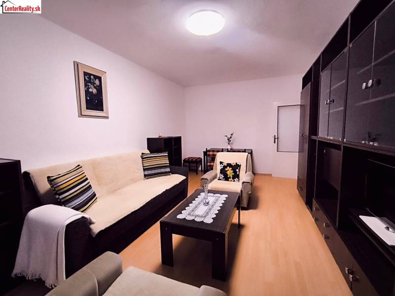 ‼️  PRENÁJOM  - 2 IZBOVÉHO BYTU, PARTIZÁNSKE SÍDLISKO ŠÍPOK ‼️ - Obývacia izba so sedačkou, dekoratívnymi vankúšmi a podlahou s dreveným dekorom v 2-izbovom byte.