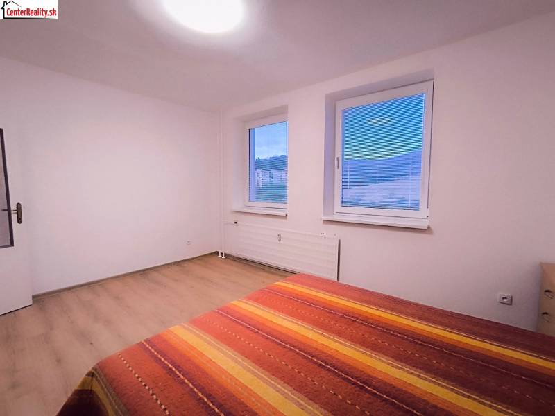‼️  PRENÁJOM  - 2 IZBOVÉHO BYTU, PARTIZÁNSKE SÍDLISKO ŠÍPOK ‼️ - Svetlá izba s dvoma oknami, posteľou a podlahou s dreveným dekorom.