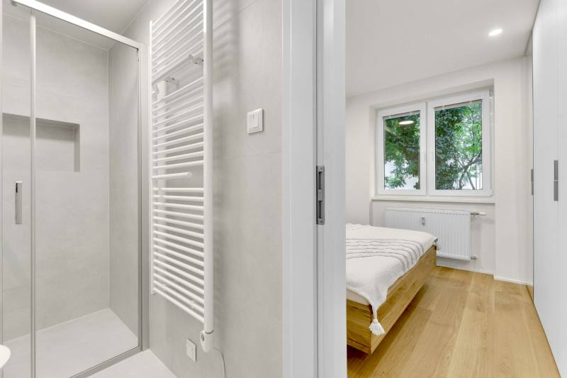 I Na predaj zrekonštruovaný 4i byt v Ružinove, Miletičova - Kúpeľňa so sprchovým kútom a spálňa v 4-izbovom byte, podlaha s dreveným dekorom.