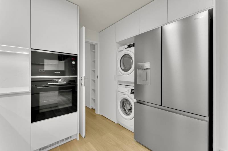 I Na predaj zrekonštruovaný 4i byt v Ružinove, Miletičova - Kuchyňa v 4-izbovom byte s práčkou, sušičkou, rúrou a chladničkou, podlaha s dreveným dekorom.