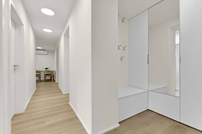 I Na predaj zrekonštruovaný 4i byt v Ružinove, Miletičova - Chodba v 4-izbovom byte s podlahou s dreveným dekorom a zrkadlovou stenou.