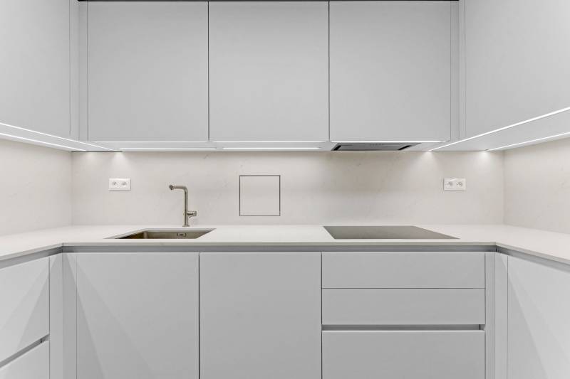 I Na predaj zrekonštruovaný 4i byt v Ružinove, Miletičova - Minimalistická kuchyňa s bielou linkou a vstavanými spotrebičmi v 4-izbovom byte.