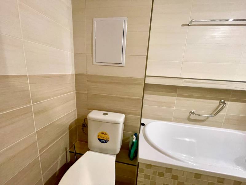 Predáj 1i čiastočne zrekonštruovaný byt s loggiou - Kúpeľňa v 1-izbovom byte so svetlým obkladom, WC a vaňou s držiakom.