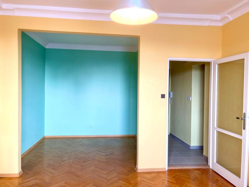 Predáj 1i čiastočne zrekonštruovaný byt s loggiou - 1-izbový byt s farebnými stenami a podlahou s dreveným dekorom.