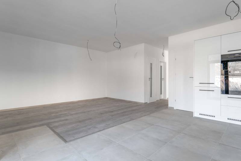 I PREDAJ novostavba 4i rodinného domu s terasou a záhradkou - Prázdna miestnosť v rodinnom dome s dlažbou a podlahou s dreveným dekorom.