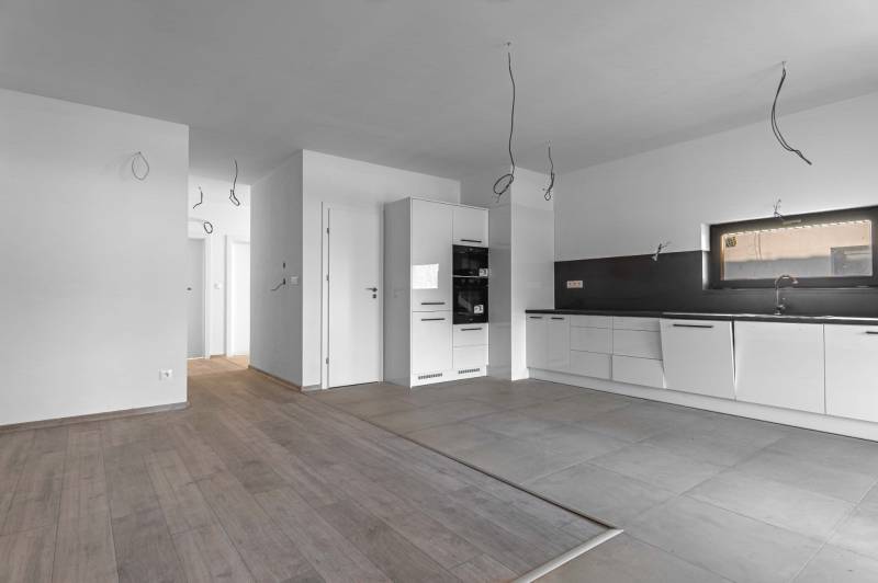 I PREDAJ novostavba 4i rodinného domu s terasou a záhradkou - Biela kuchyňa v rodinnom dome, podlaha s dreveným dekorom a dlažba.