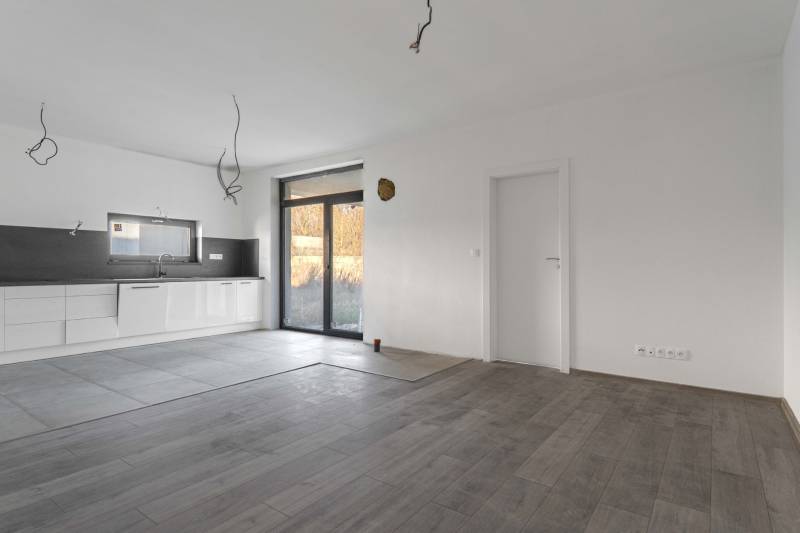 I PREDAJ novostavba 4i rodinného domu s terasou a záhradkou - Kuchyňa v rodinnom dome s podlahou s dreveným dekorom a veľkým oknom.