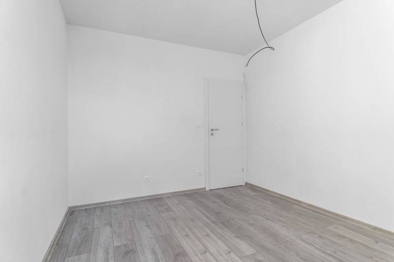 I PREDAJ novostavba 4i rodinného domu s terasou a záhradkou - Prázdna miestnosť v rodinnom dome s podlahou s dreveným dekorom a bielymi stenami.