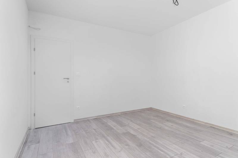 I PREDAJ novostavba 4i rodinného domu s terasou a záhradkou - Prázdna miestnosť s bielymi stenami a podlahou s dreveným dekorom v rodinnom dome.