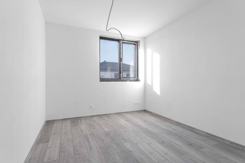 I PREDAJ novostavba 4i rodinného domu s terasou a záhradkou - Prázdna miestnosť s podlahou s dreveným dekorom a veľkým oknom v rodinnom dome.