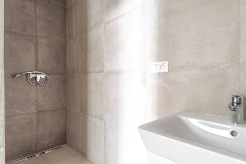 I PREDAJ novostavba 4i rodinného domu s terasou a záhradkou - Sprchový kút s obkladom a bielym umývadlom v rodinnom dome.