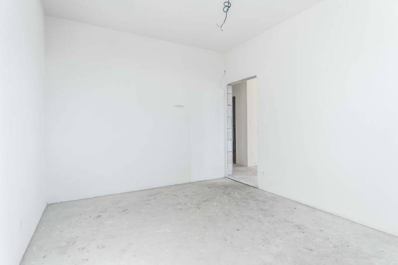 I NA PREDAJ 4i rodinný dom s veľkým pozemkom v Galante - Prázdna miestnosť s bielymi stenami a betónovou podlahou v rodinnom dome.