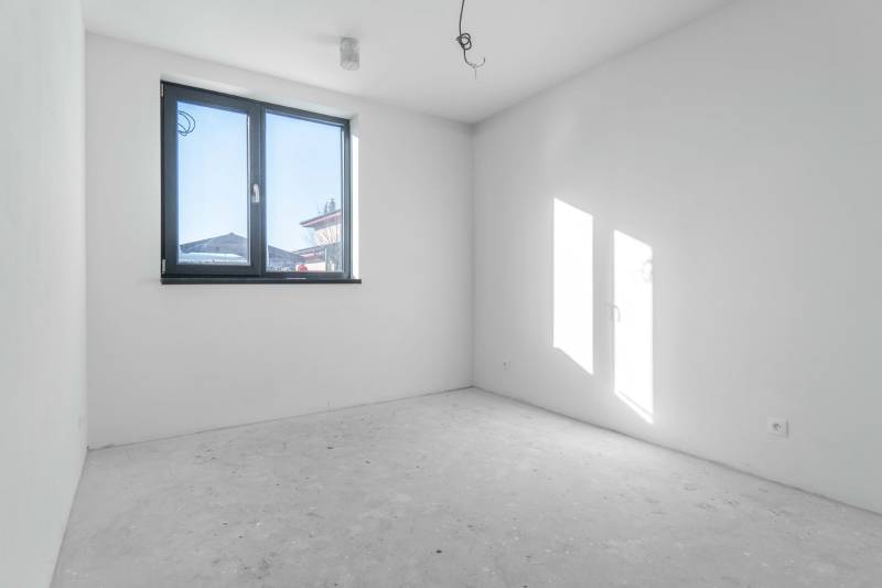 I NA PREDAJ 4i rodinný dom s veľkým pozemkom v Galante - Prázdna izba v rodinnom dome so sivou podlahou a veľkým oknom.