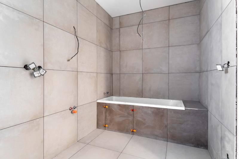 I NA PREDAJ 4i rodinný dom s veľkým pozemkom v Galante - Kúpeľňa v rodinnom dome s veľkými svetlosivými obkladačkami a neosadenou vaňou.