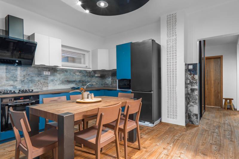 I Predaj štýlového tehlového domu v Rajke pri Bratislave - Kuchyňa v rodinnom dome s dreveným stolom a podlahou s dreveným dekorom.