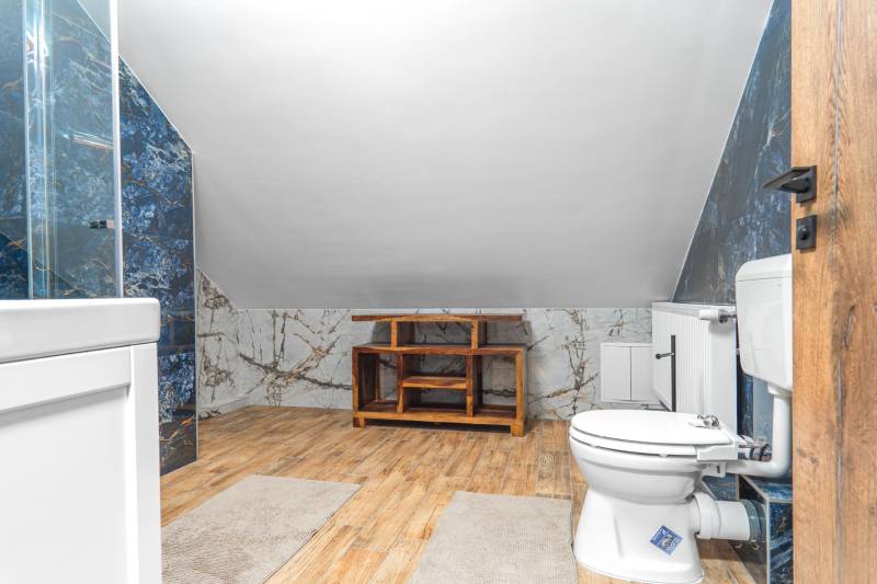 I Predaj štýlového tehlového domu v Rajke pri Bratislave - Kúpeľňa v rodinnom dome s podlahou s dreveným dekorom a mramorovými obkladmi.