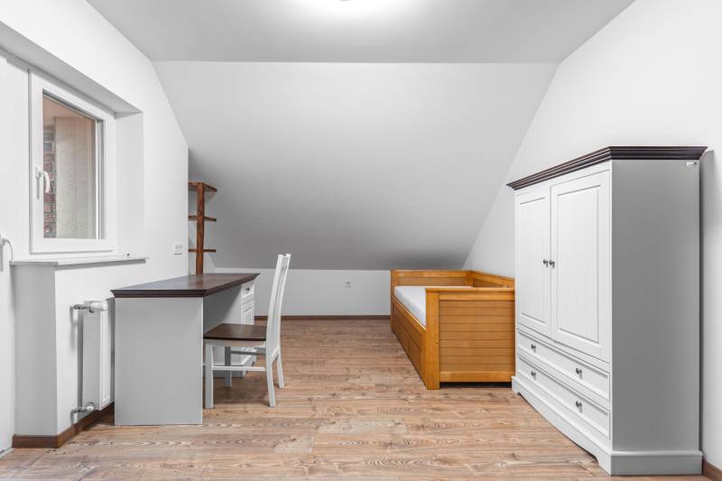 I Predaj štýlového tehlového domu v Rajke pri Bratislave - Izba v rodinnom dome s dreveným nábytkom a podlahou s dreveným dekorom.