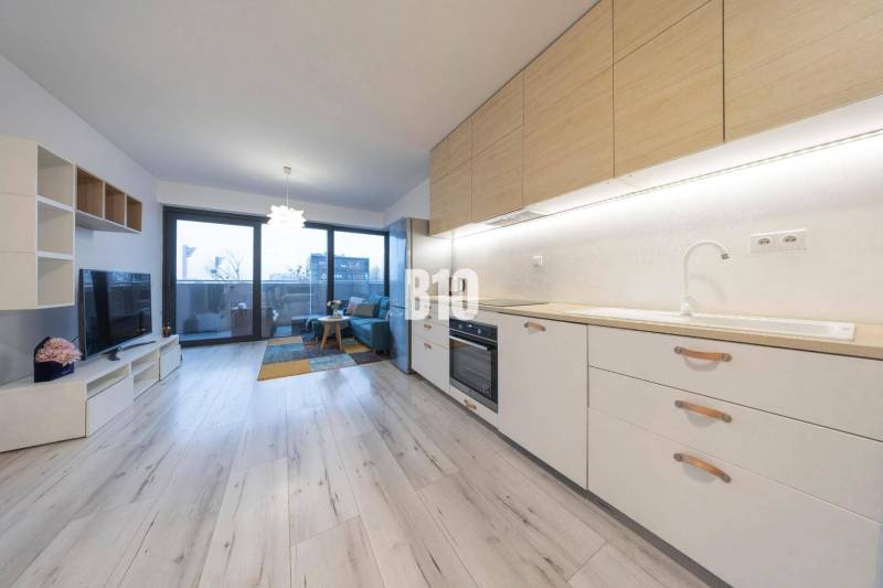 TEHELNÉ POLE | 1-izbový byt s priestrannou terasou - Interiér 1-izbového bytu s kuchynskou linkou a podlahou s dreveným dekorom.