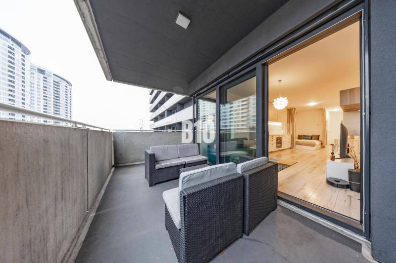 TEHELNÉ POLE | 1-izbový byt s priestrannou terasou - Balkón s výhľadom a priestranný interiér 1-izbového bytu s podlahou s dreveným dekorom.