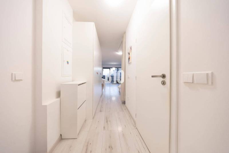 TEHELNÉ POLE | 1-izbový byt s priestrannou terasou - Úzka chodba v 1-izbovom byte s bielym nábytkom a svetlou podlahou.