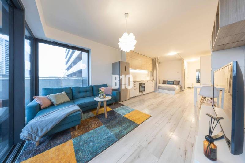 TEHELNÉ POLE | 1-izbový byt s priestrannou terasou - Obývacia miestnosť v 1-izbovom byte s rozkladacou sedačkou a podlahou s dreveným dekorom.