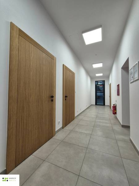 Na prenájom  plne zariadený apartmán na Južnej triede 44, Košice - Chodba so svetlými dlaždicami, drevenými dverami a svetlami na strope v 1-izbovom byte.