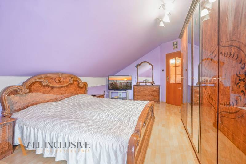 NA PREDAJ RODINNÉ DOMY S GARÁŽOU, DUNAJSKÁ STREDA - Podkrovná spálňa s dreveným nábytkom a fialovými stenami v rodinnom dome.