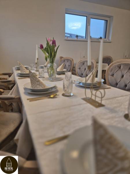 Ponúkame na prenájom zariadený podnikateľský priestor - kaviareň&bar. - Stôl s bielym obrusom, taniere, poháre, kvetiny a prikrývky stoličiek v gastro priestoroch.