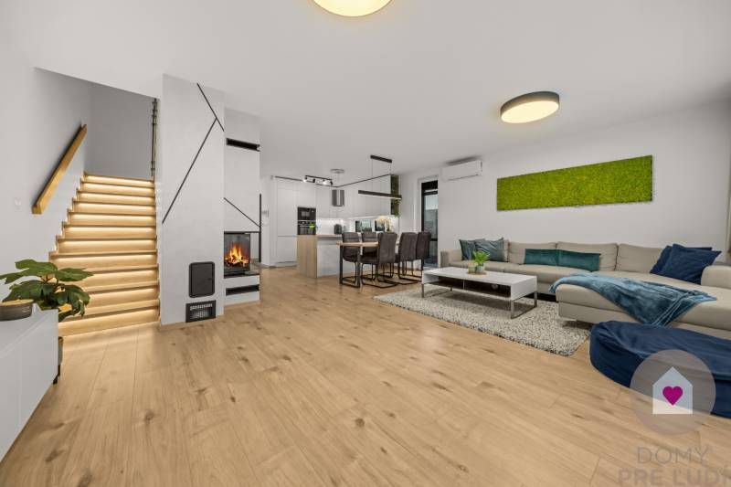 ROVINKA-Prenájom modernej, zariadenej novostavby 4 izbového rod.domu - Obývačka 4-izbového bytu s podlahou s dreveným dekorom, krbom a moderným schodiskom.